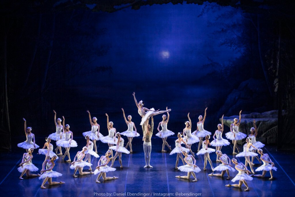O Lago dos Cisnes. Imagem de bailarinos no palco.